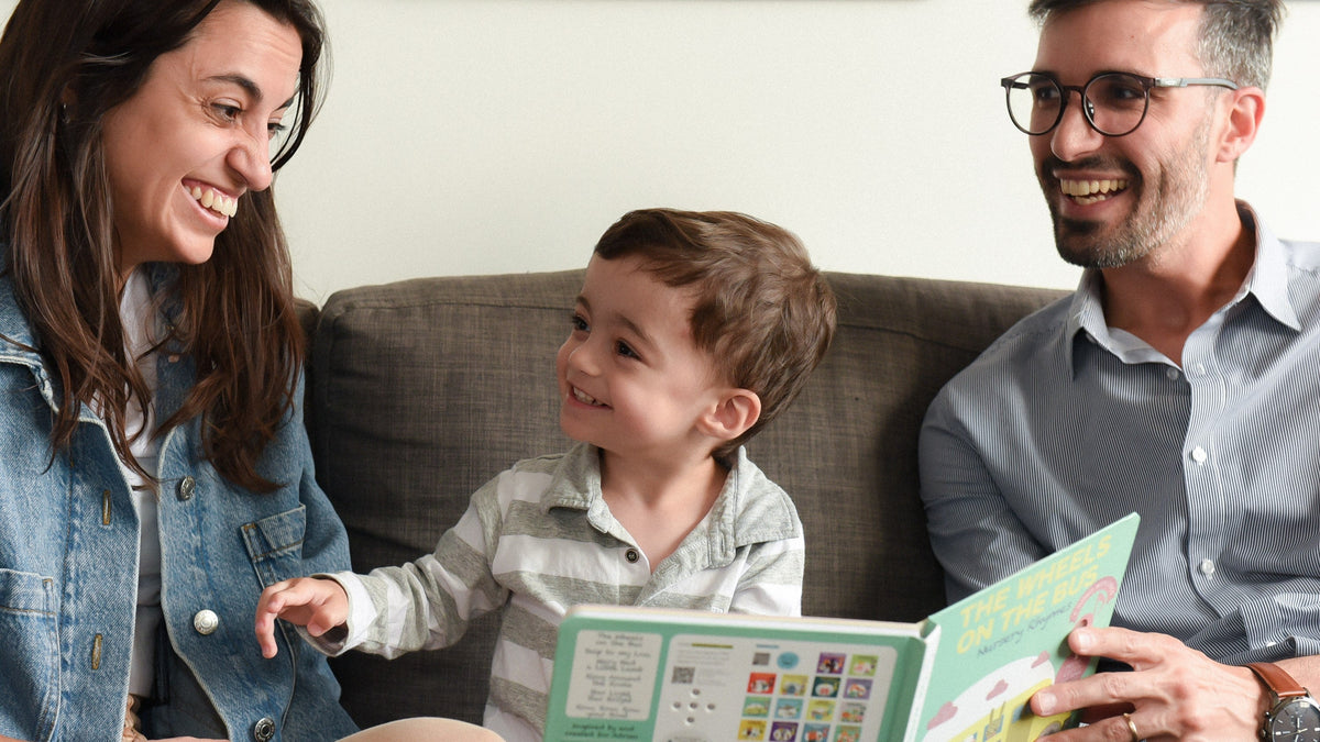 A Mom and a Dad are reading a book to their toddler. Best parenting books, toddler, kids activities, education.
